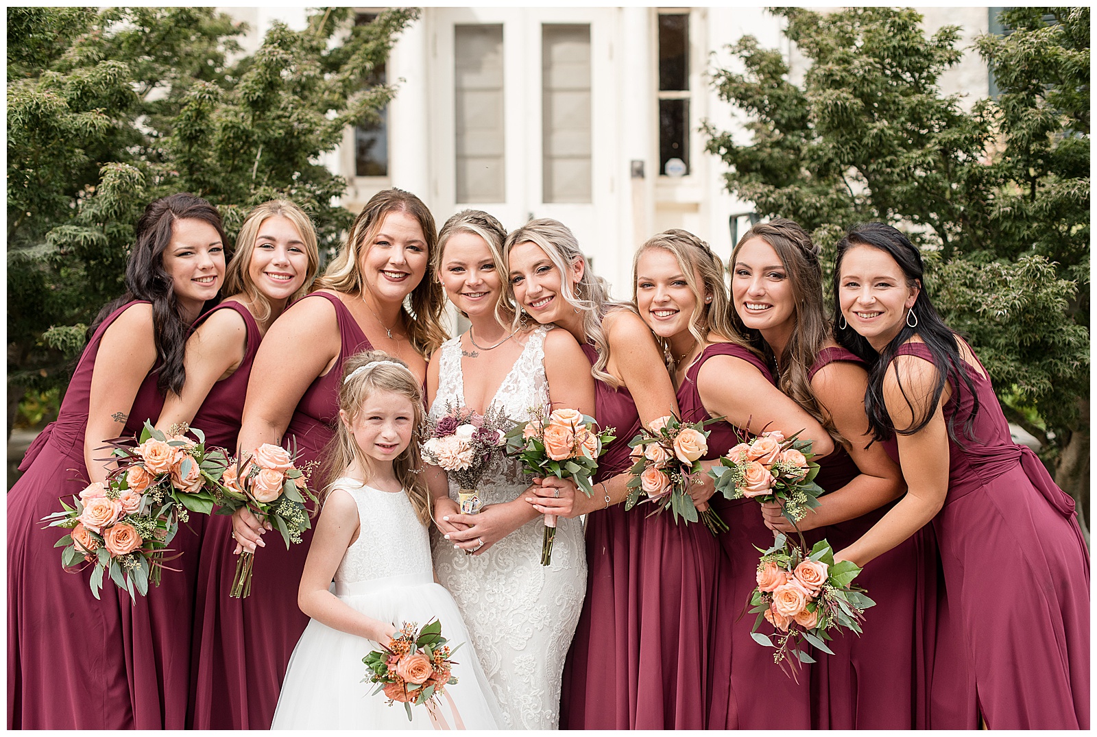 bride surrounded by flowergirl and bridesmaids in maroon dresses at hayfields country club in maryland
