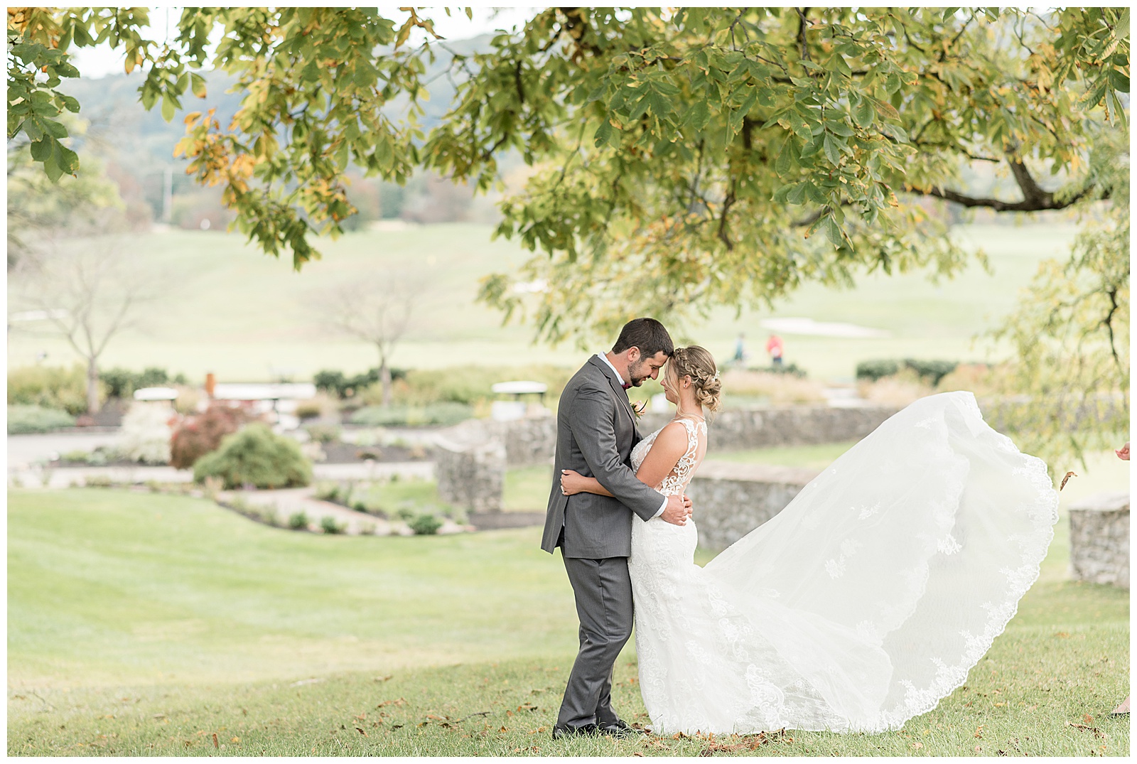 groom and bride hugging with gown blowing in breeze at hayfields country club