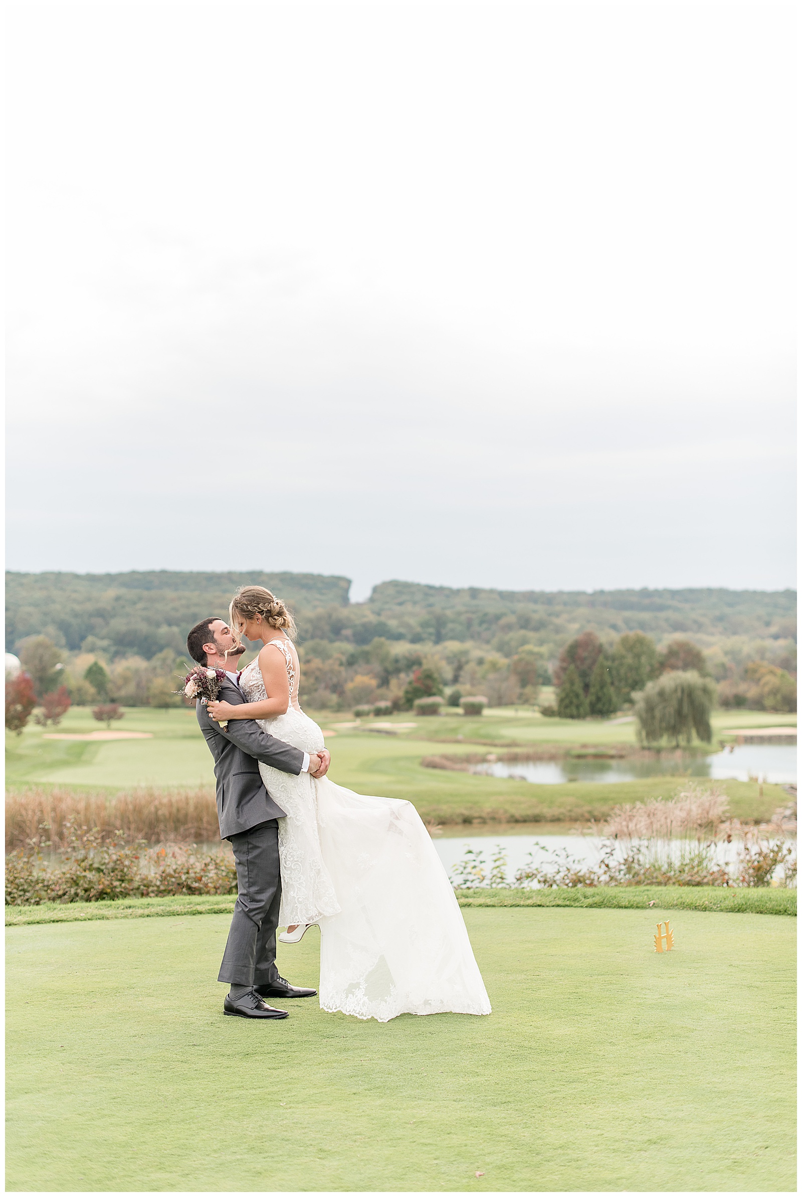 groom lifts bride while kissing on golf course at hayfields country club in maryland