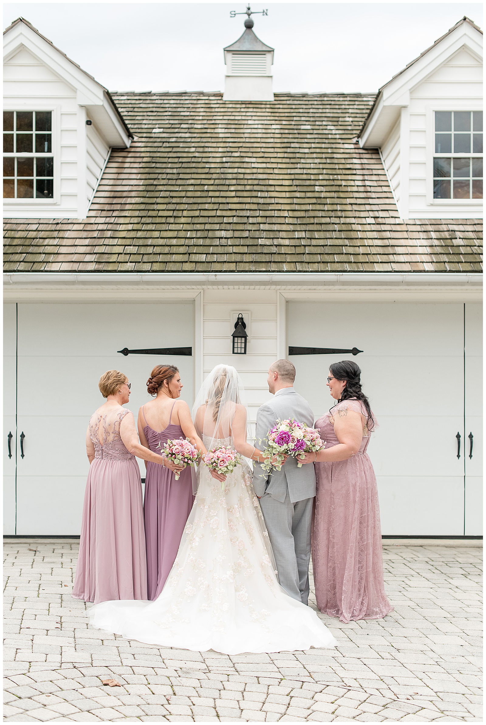 bride bridesmaids and brideman backs to camera in front of white barn doors at bluestone estate