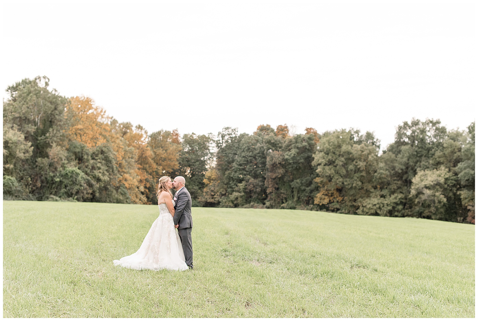 groom kissing bride in grass meadow on beautiful fall day at bluestone estate