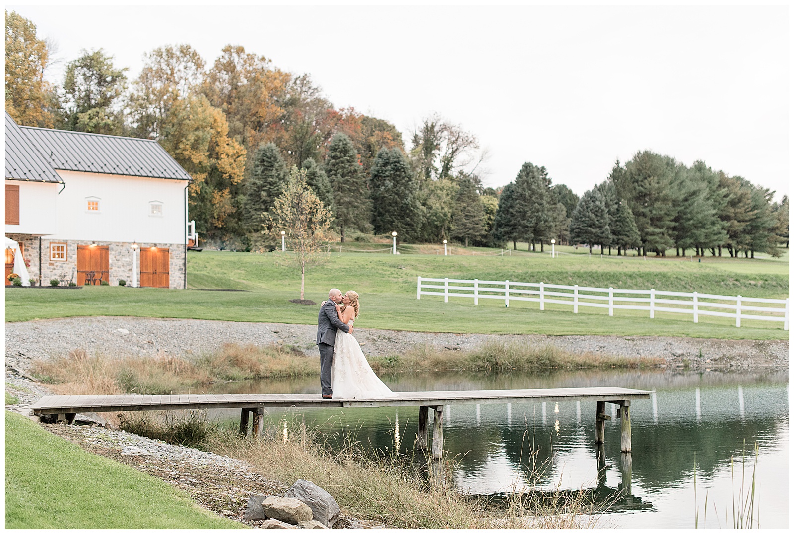 bride and groom kissing on dock by pond on beautiful fall day at bluestone estate