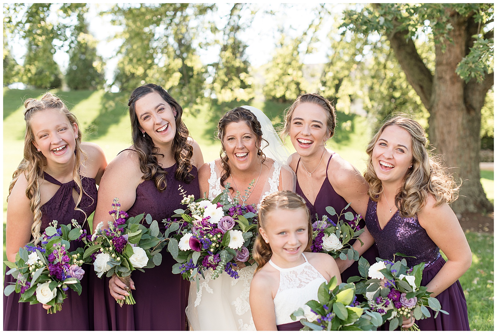 bridesmaids laughing at camera holding floral bouquets