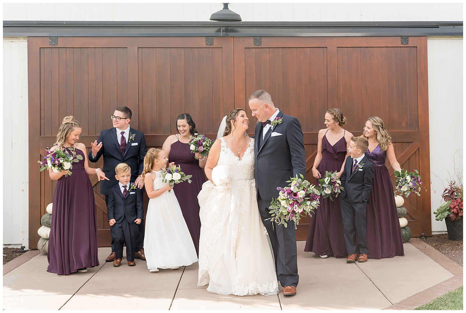 bridal party in front of large barn doors walking and talking