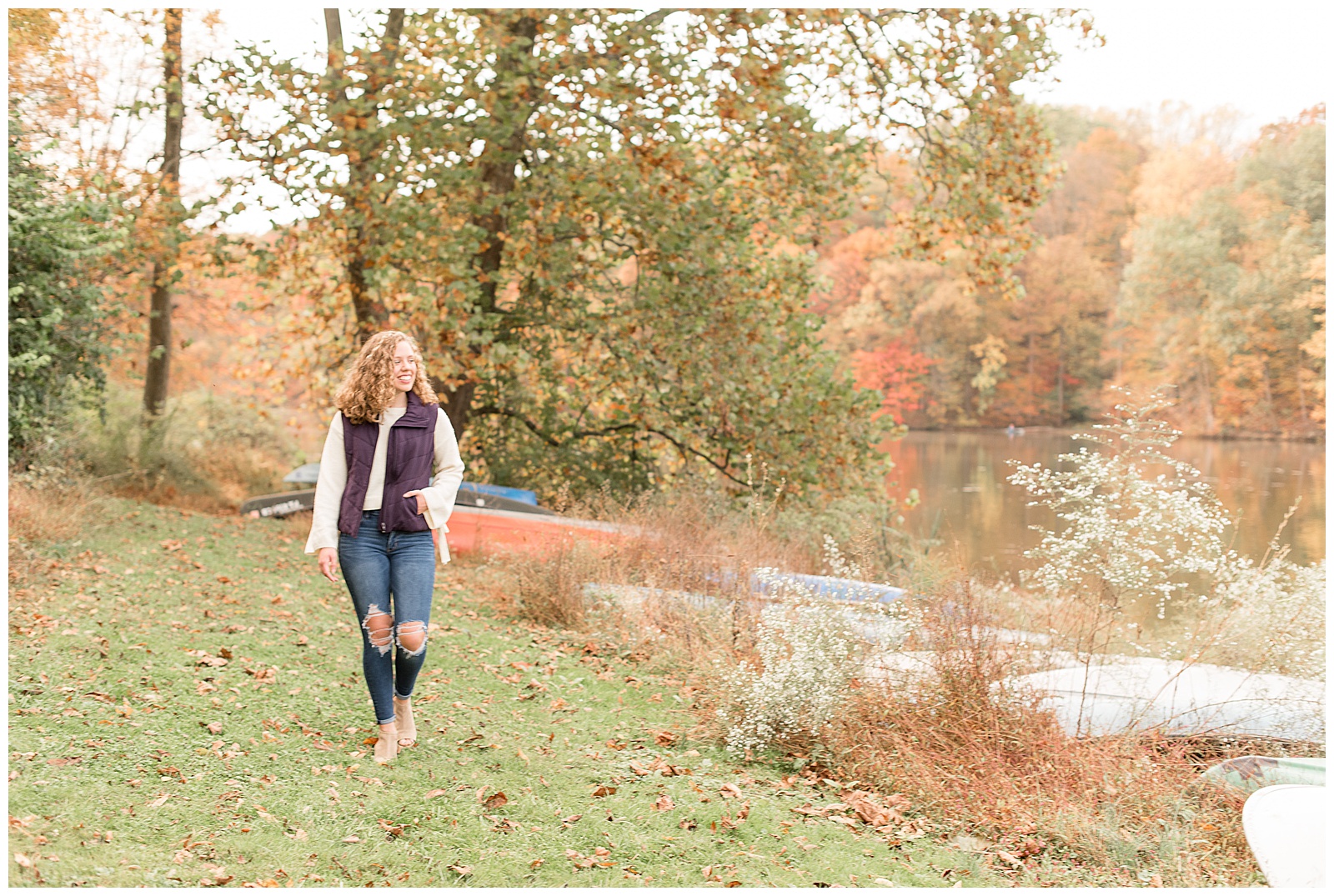 senior girl walking along speedwell forge lake near canoes and trees in lancaster pennsylvania