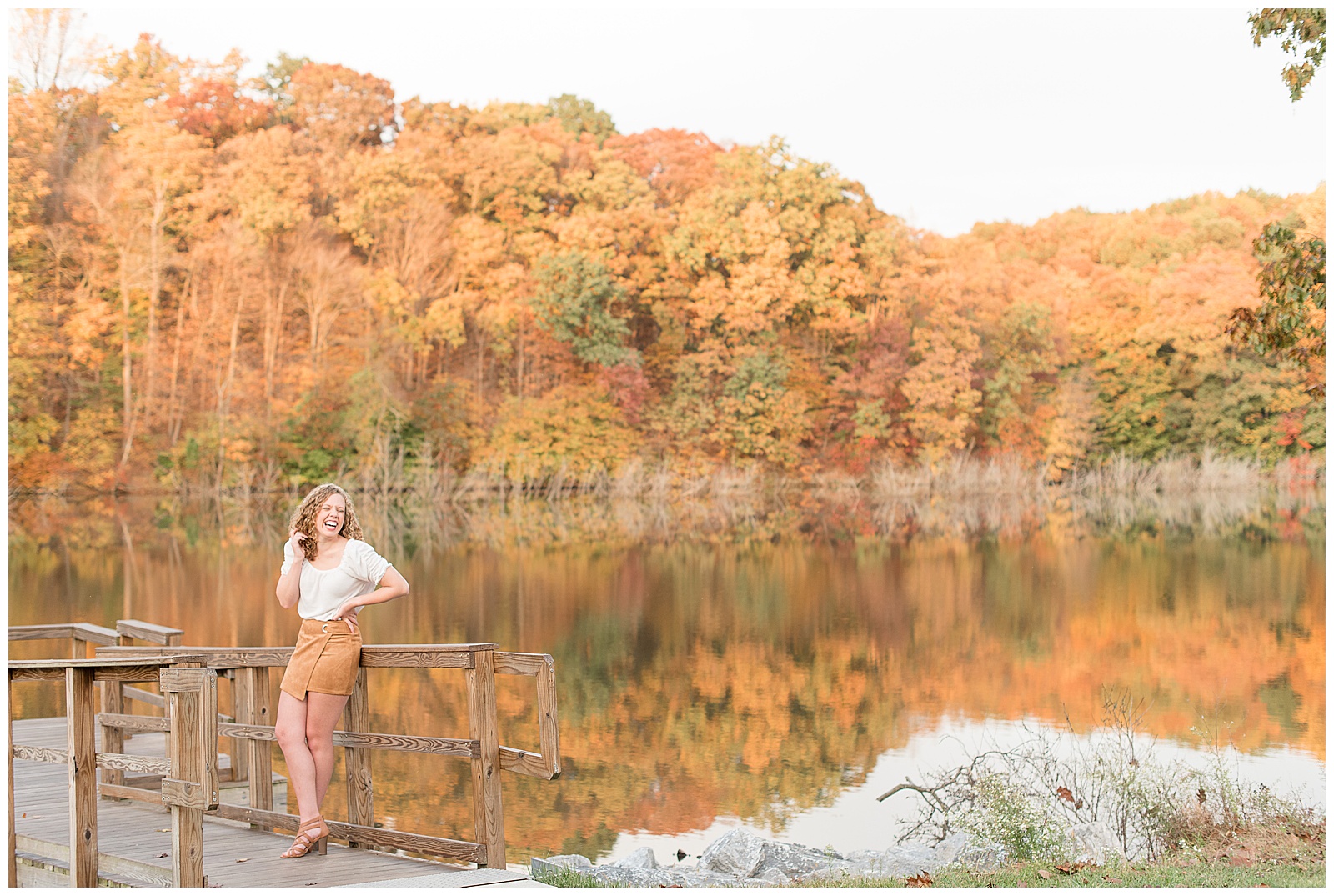 senior girl on wooden dock by speedwell forge lake with colorful trees on fall day