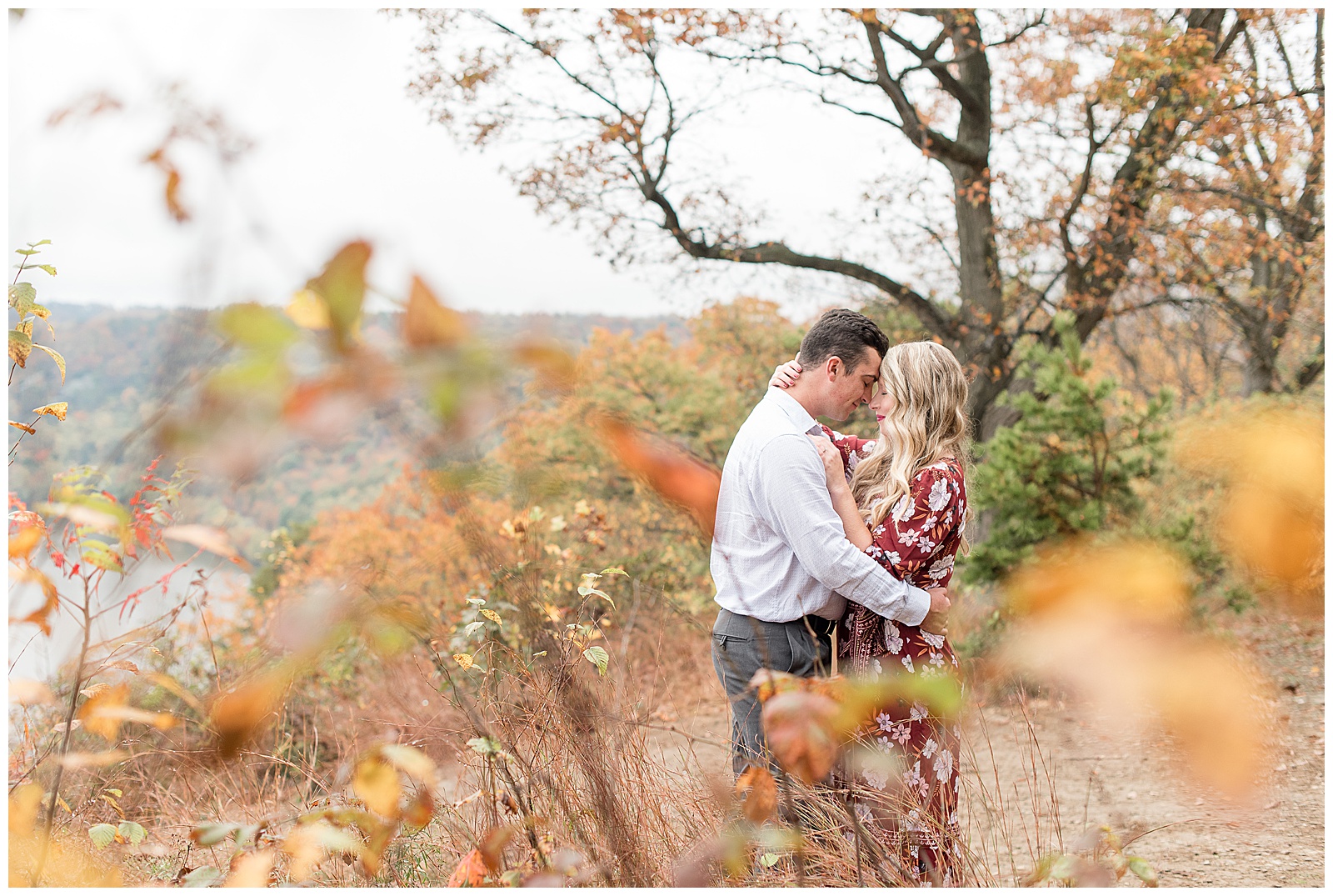 couple hugging tightly among fall wildflowers and trees at pinnacle point