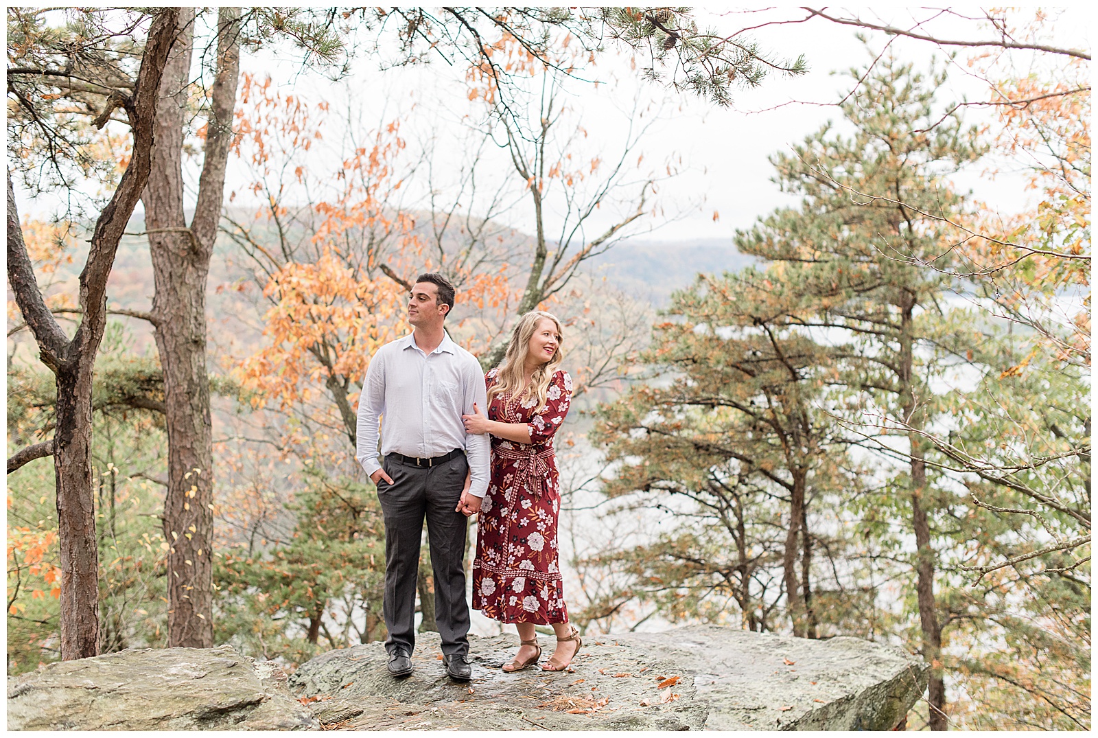 couple standing close looking in opposite directions among trees on large rock at pinnacle point