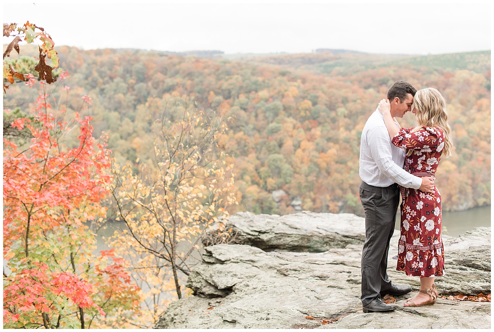 couple hugging atop large rock lookout at pinnacle point on colorful fall day in central pennsylvania