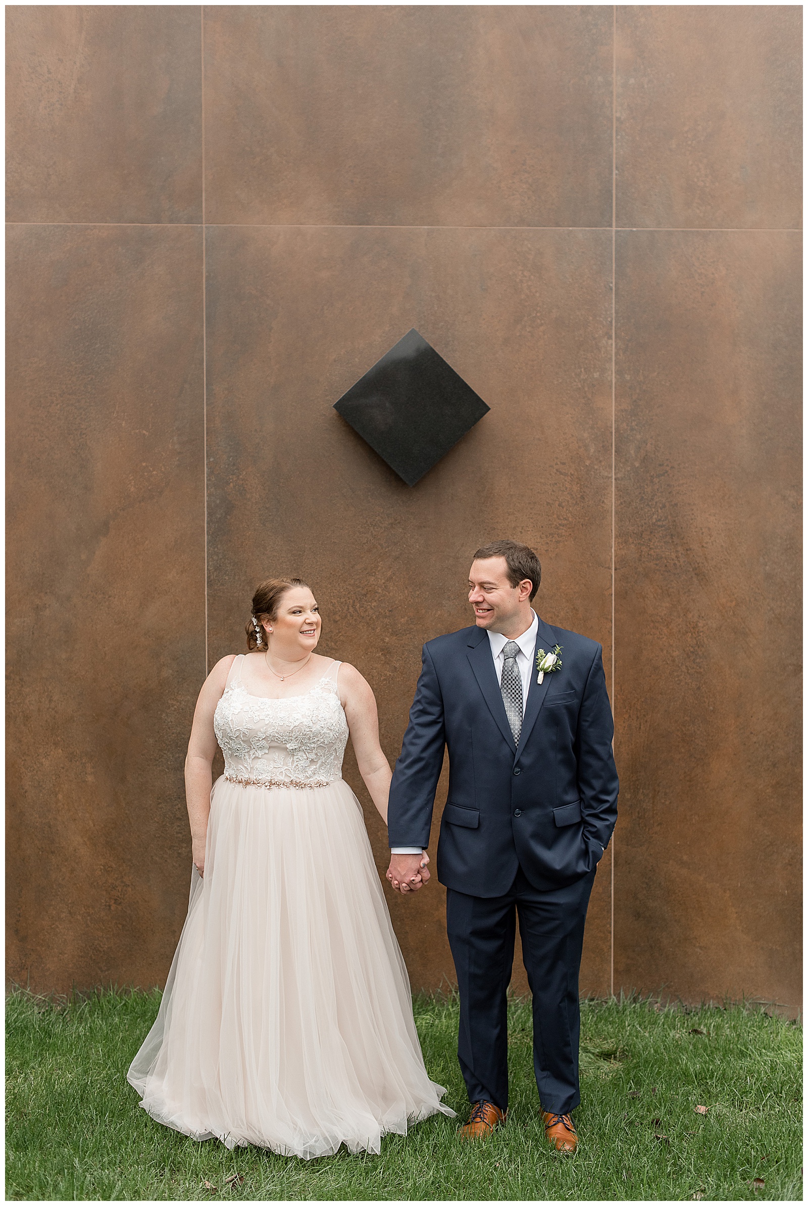 bride and groom holding hands by wooden wall smiling at eden resort
