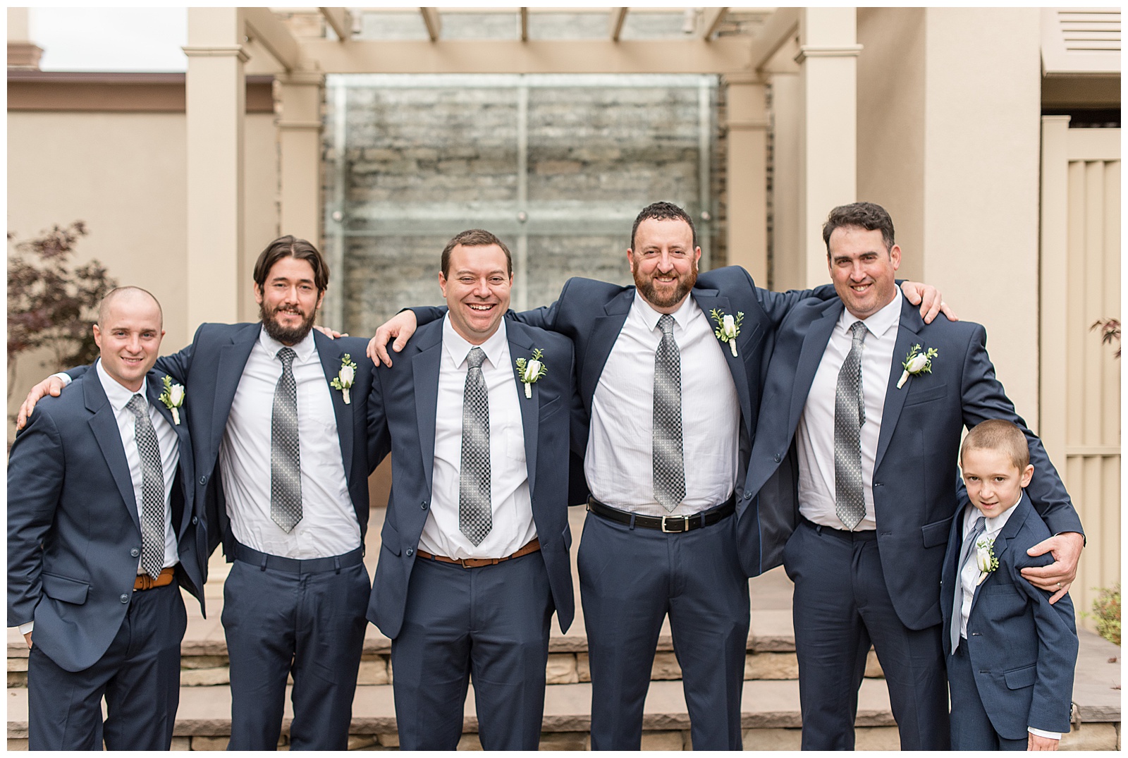 groom and groomsmen smiling with arms over shoulders by wooden trellis in lancaster pennsylvania