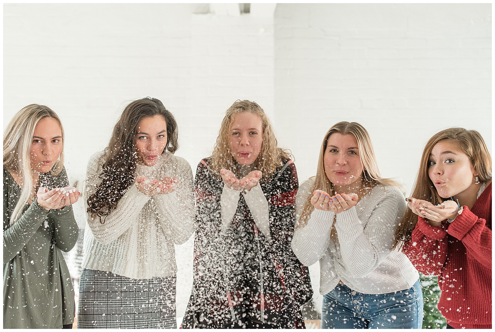 girls smiling blowing snowflakes towards camera in white room at hingeworks in lancaster pennsylvania