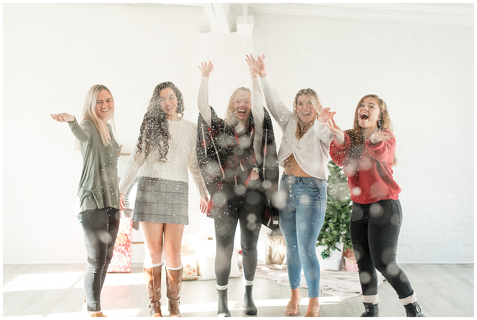 group of senior girls gathered together tossing snowflakes into the air and smiling at hingeworks