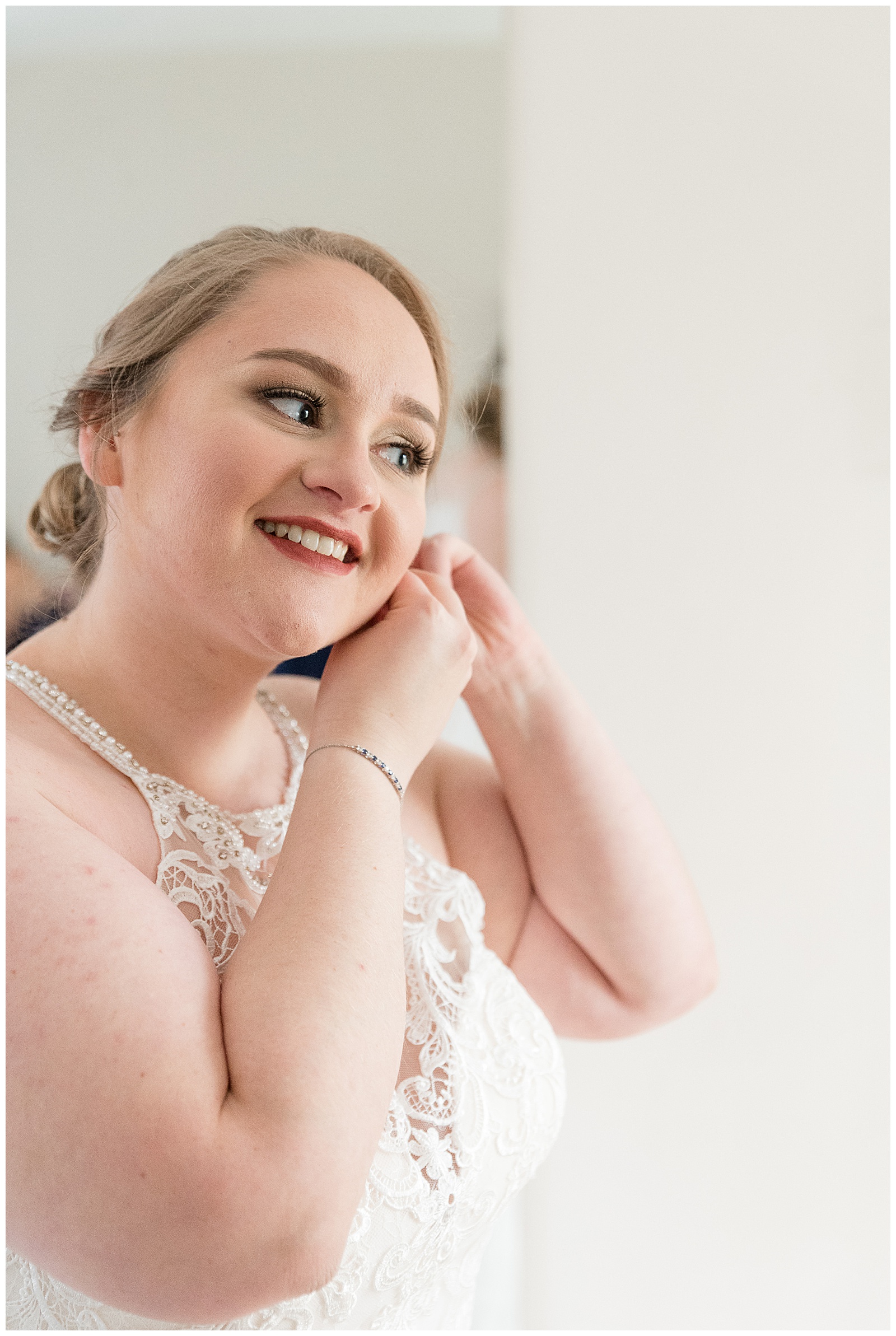 bride smiling as she puts on her earring at riverdale manor in lancaster pennsylvania
