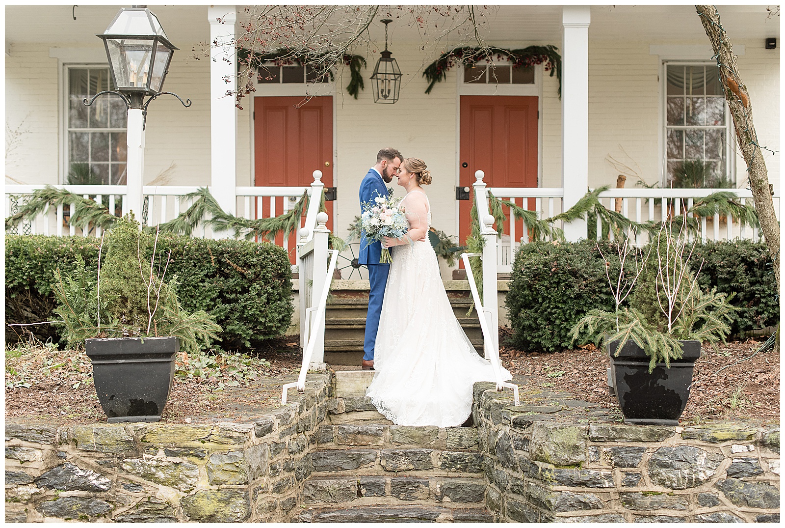bride and groom almost kiss on steps of white home decorated with garland at riverdale manor