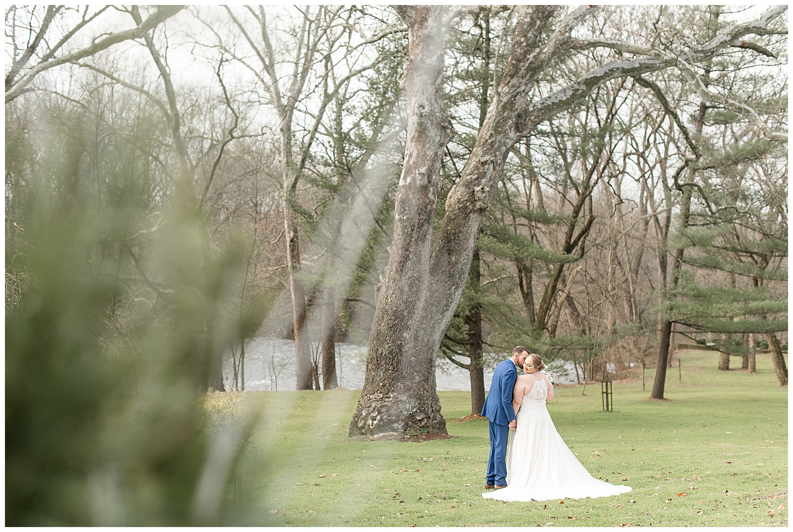 couple kissing under oak tree with their backs to the camera on winter day at riverdale manor