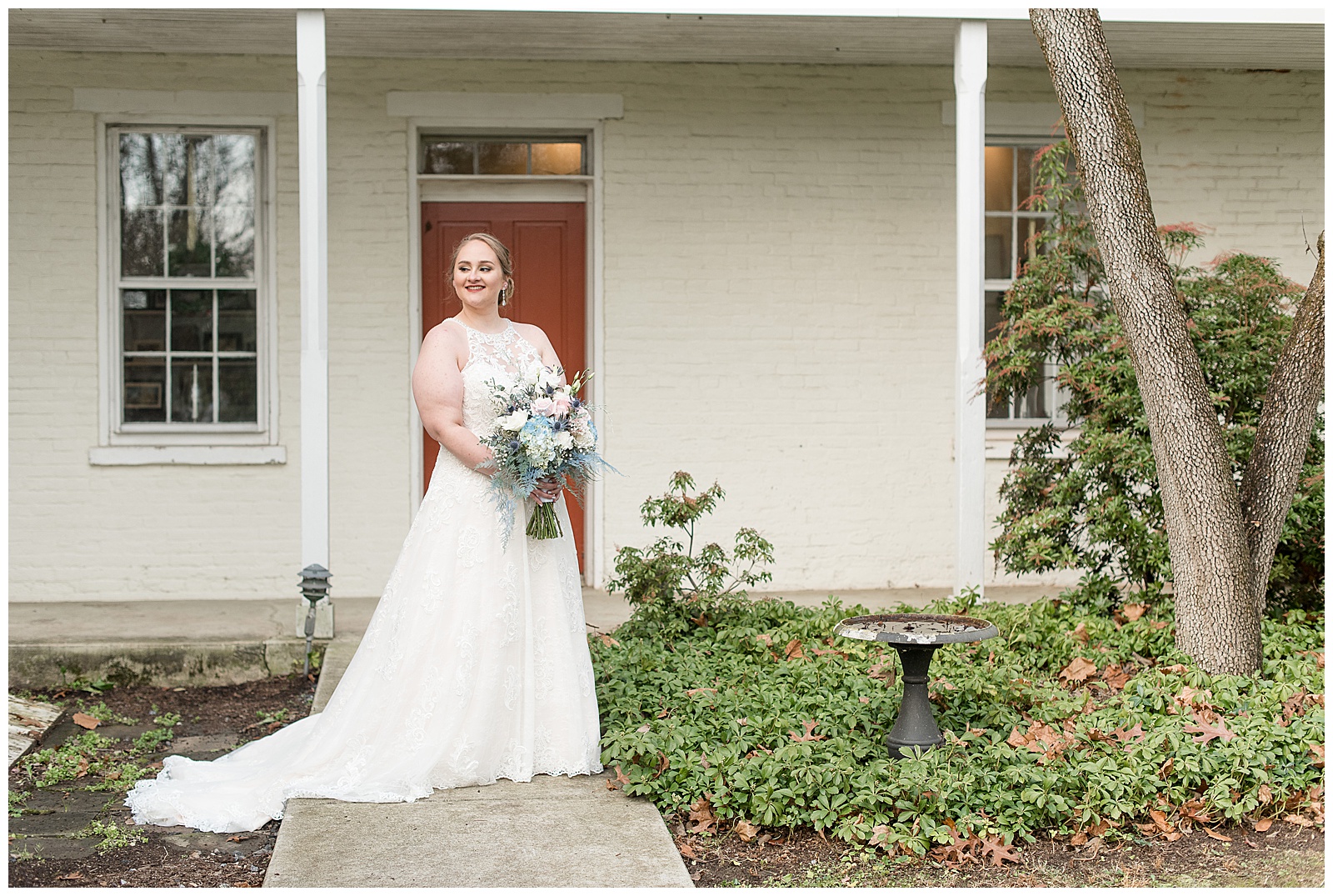 bride holding bouquet in sleeveless gown on walkway by red door in lancaster pennsylvania