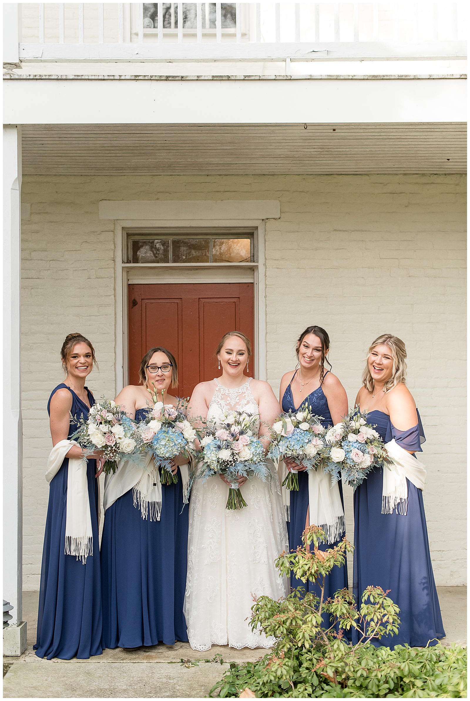 bride with bridesmaids holding bouquets wearing dark blue gowns with white scarves in lancaster pennsylvania