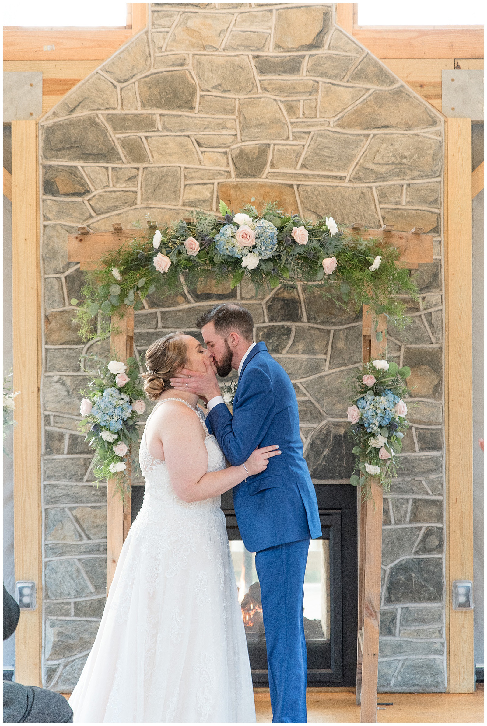 couple kissing by stone fireplace during wedding ceremony in lancaster pennsylvania