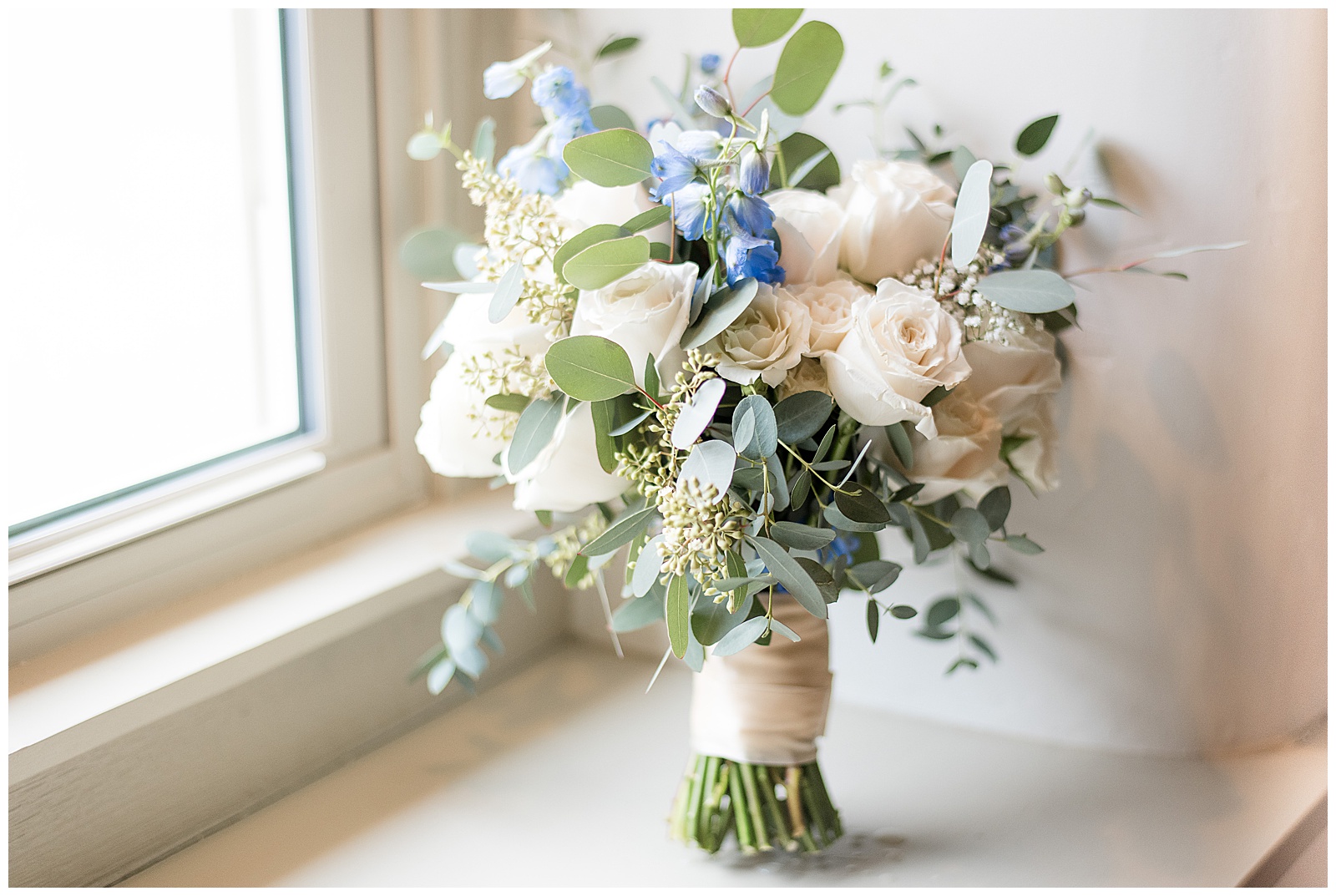 bridal bouquet displayed on windowsill with ivory roses blue flowers and eucalyptus in lancaster pennsylvania