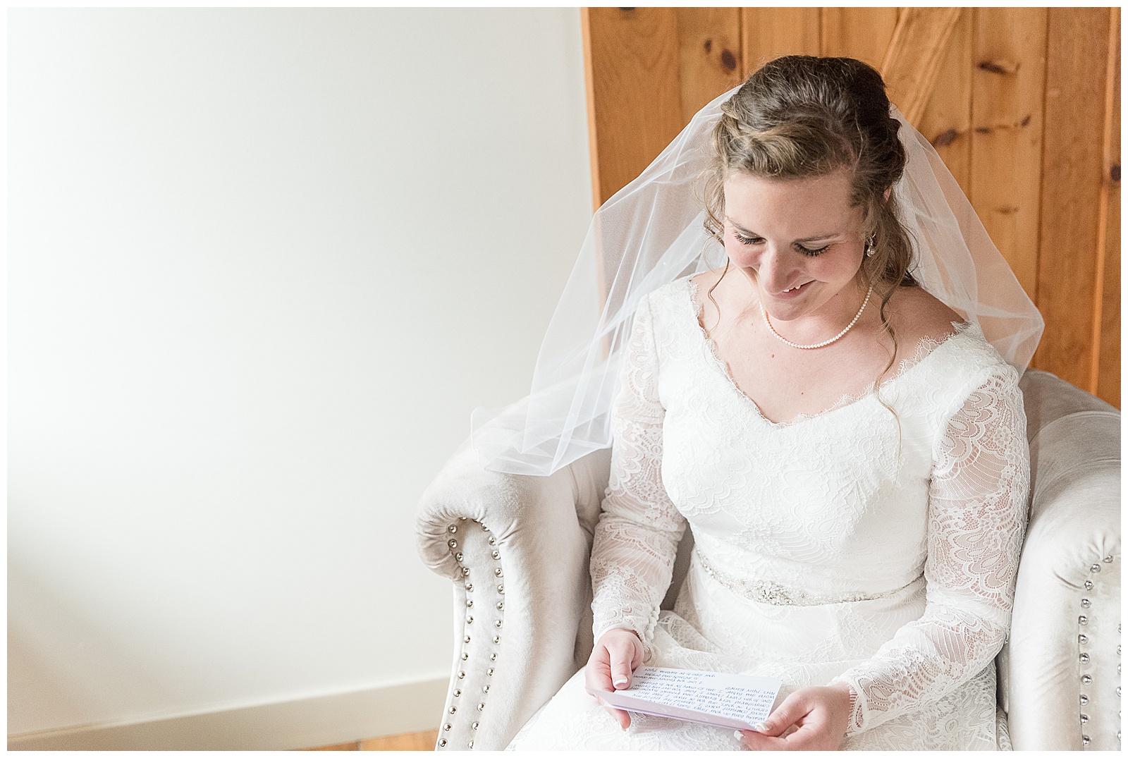 bride sitting on white chair in bridal suite reading note before ceremony in lancaster pennsylvania