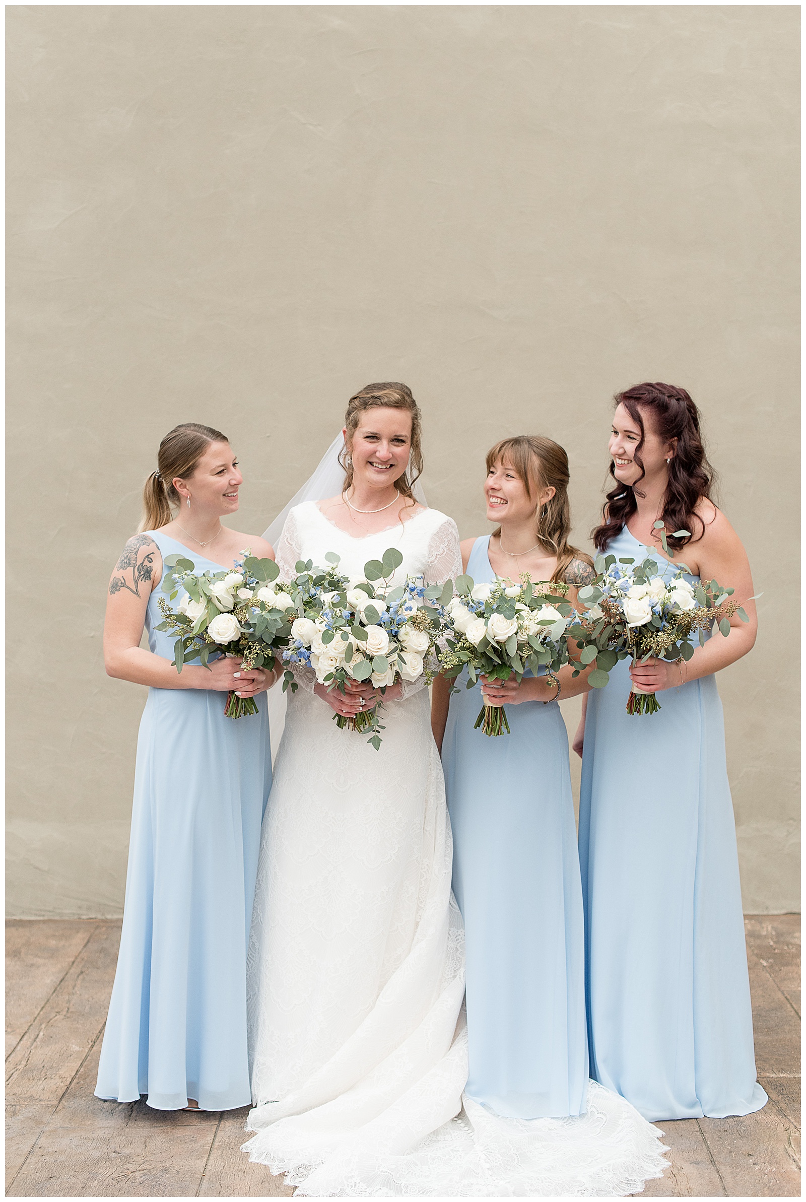 bridesmaids standing beside bride looking at her and smiling at the mill at manor falls