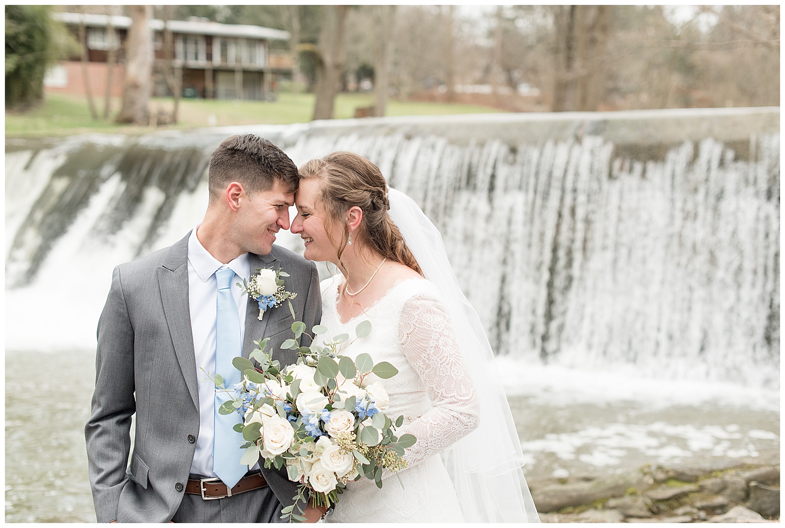 couple resting foreheads together smiling in front of waterfall at the mill at manor falls in lancaster pennsylvania