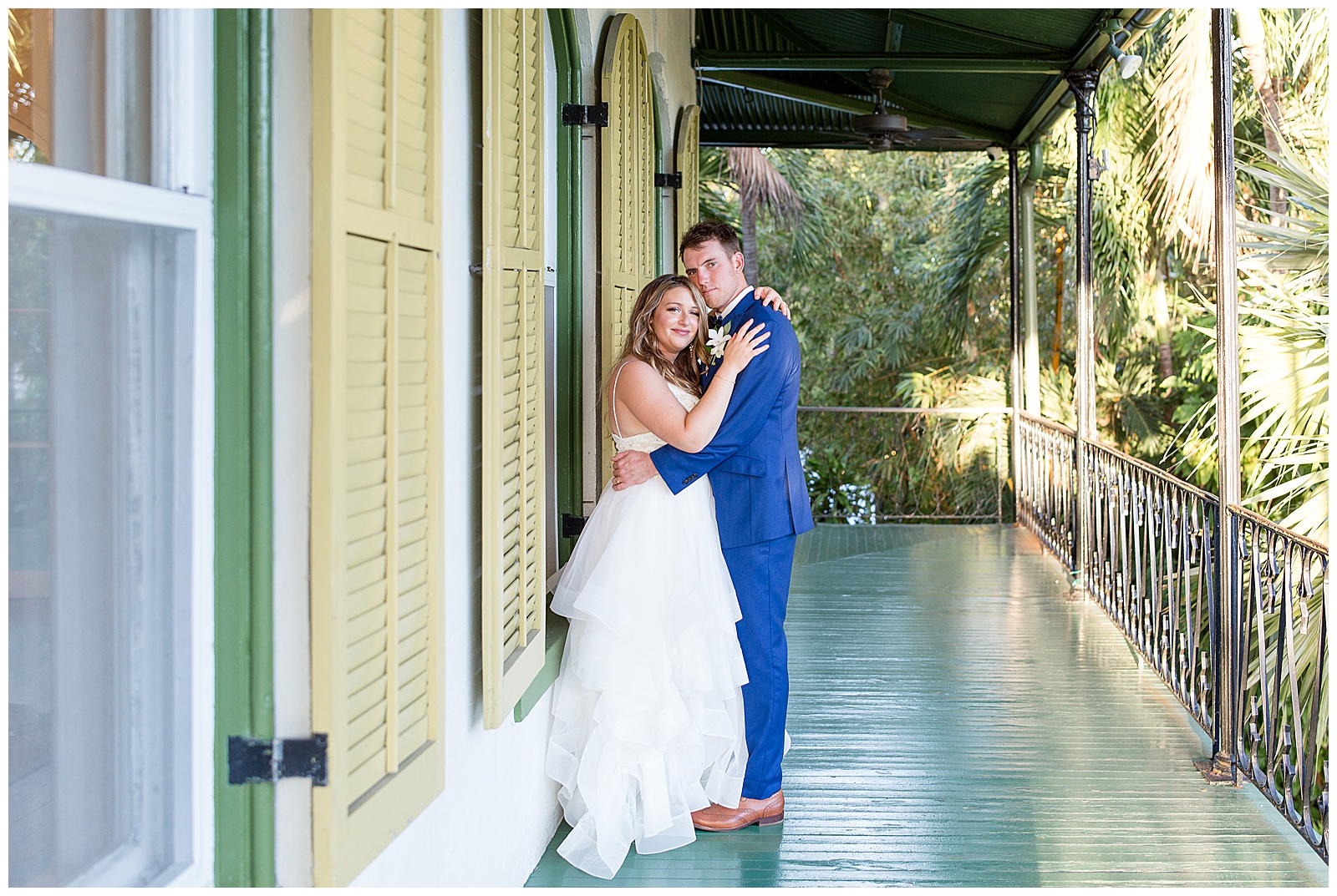 bride and groom hug tightly while standing on porch of historical home in key west florida