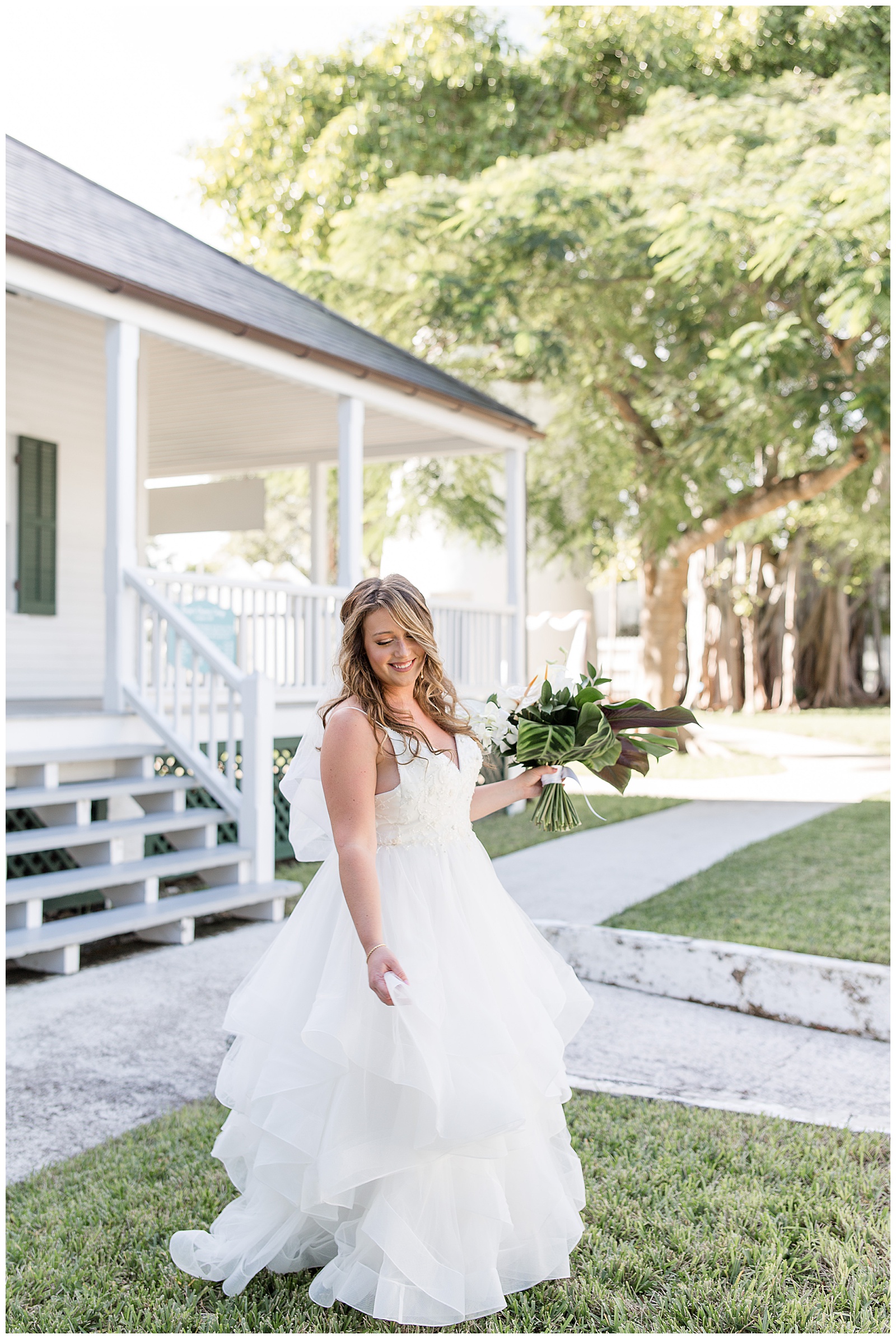 bride in sleeveless white ruffled wedding gown twirling in grass lawn at hemingway house