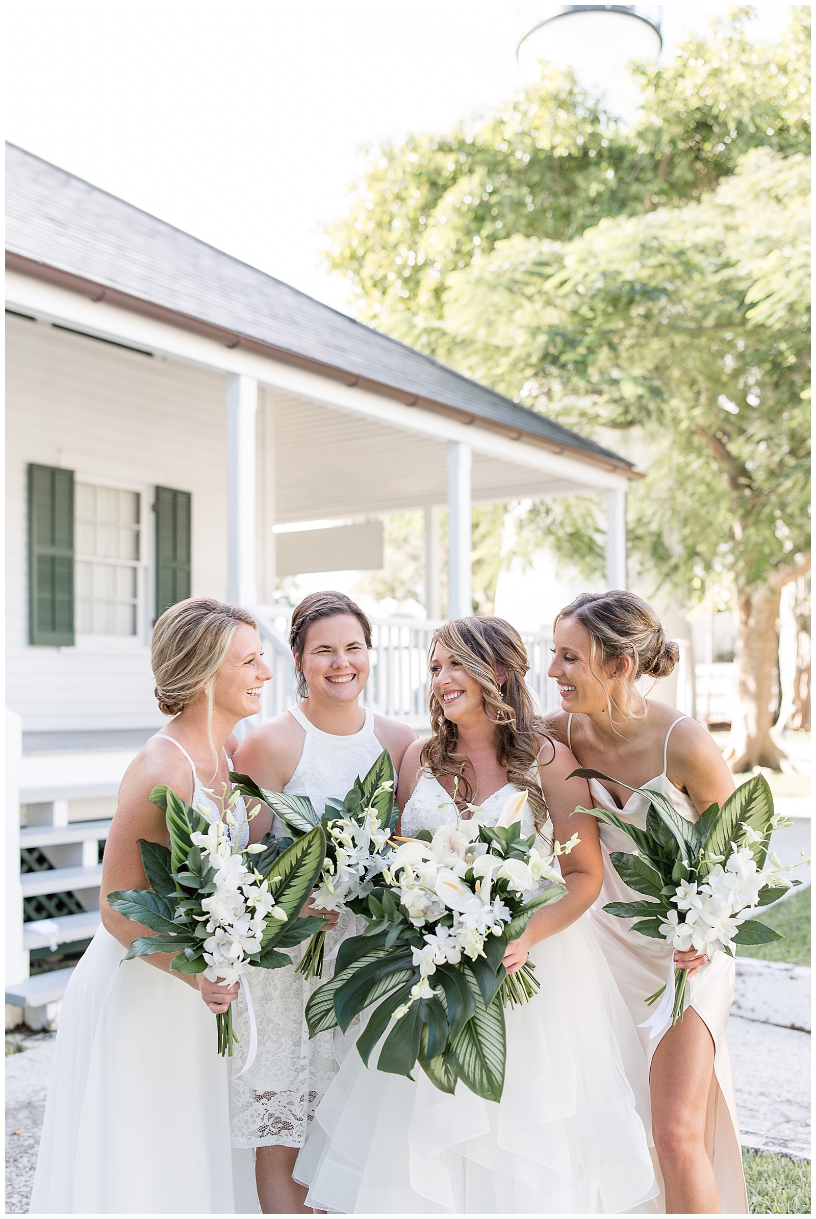 bride surrounded by her three bridesmaids who are also wearing white gowns and holding bouquets in key west florida