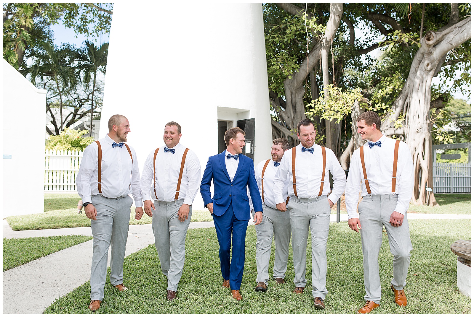 groom and groomsmen smiling as they walk towards the camera looking at each other at hemingway house