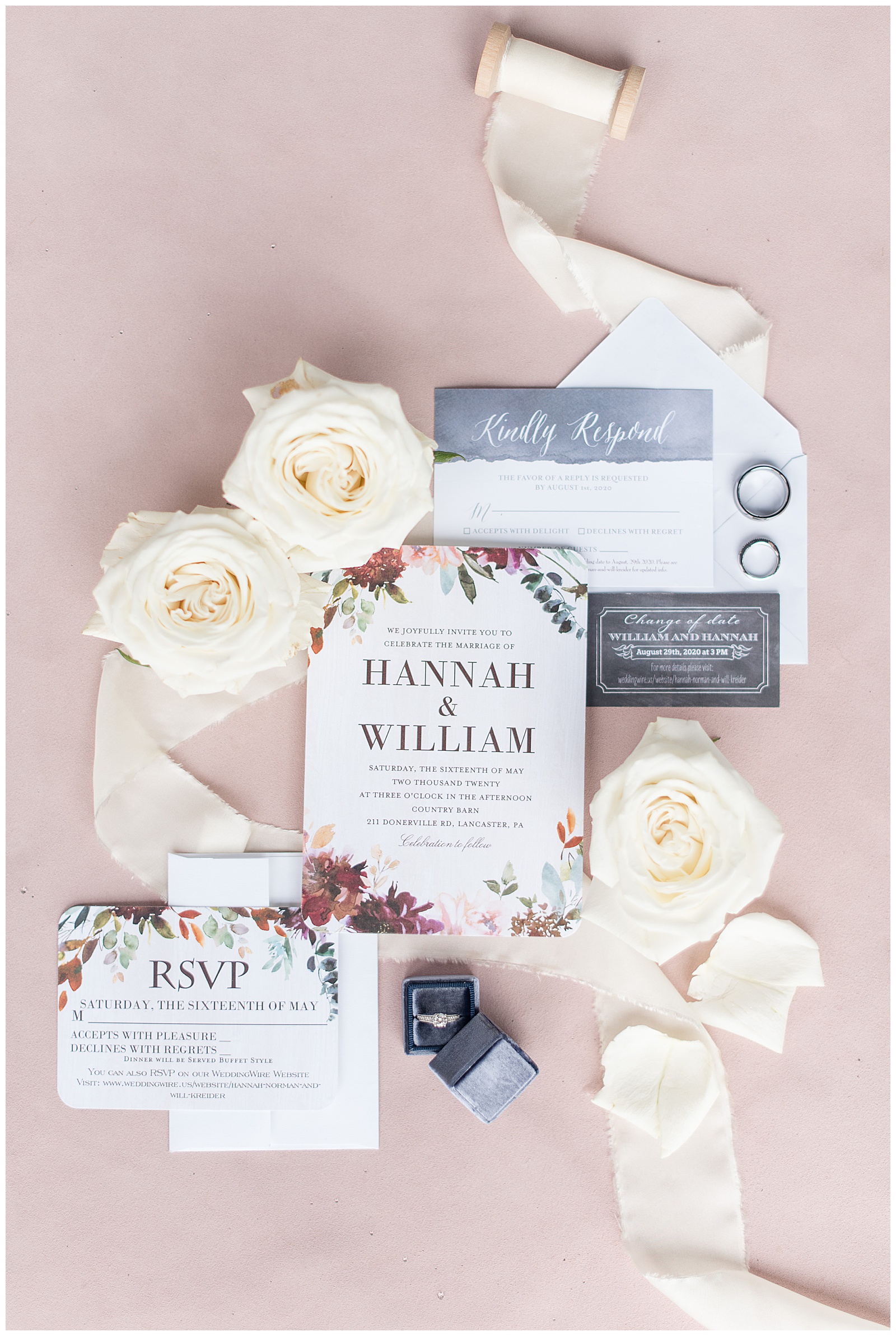 wedding invitation and rings displayed on mauve table with ivory ribbon and roses