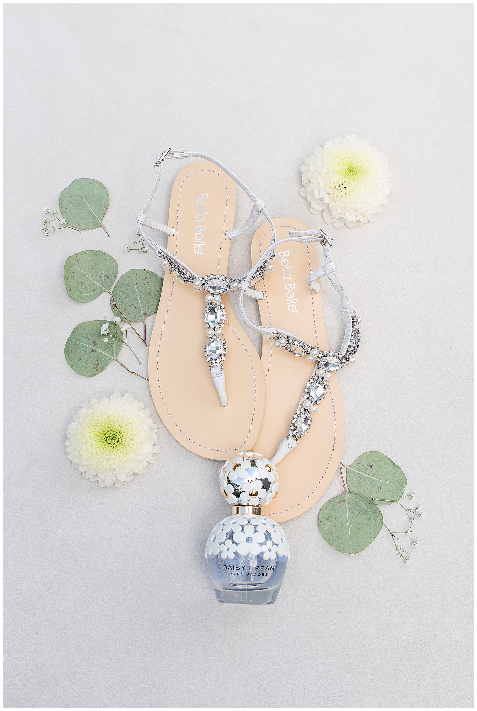 bride's sparkly sandals and perfume bottle surrounded by silver dollar eucalyptus and ivory flowers