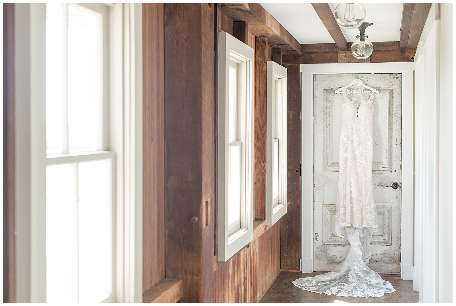bridal gown on hanger displayed hanging from door frame of rustic barn bridal suite