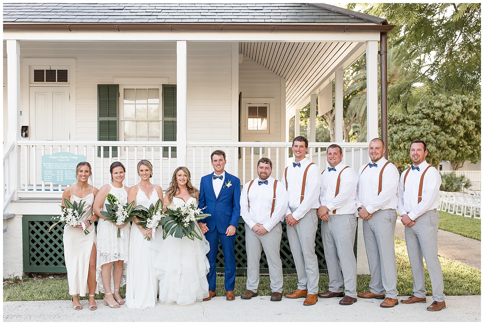 bride and groom surrounded by their bridal party on sunny wedding day outside white home at the hemingway house in florida