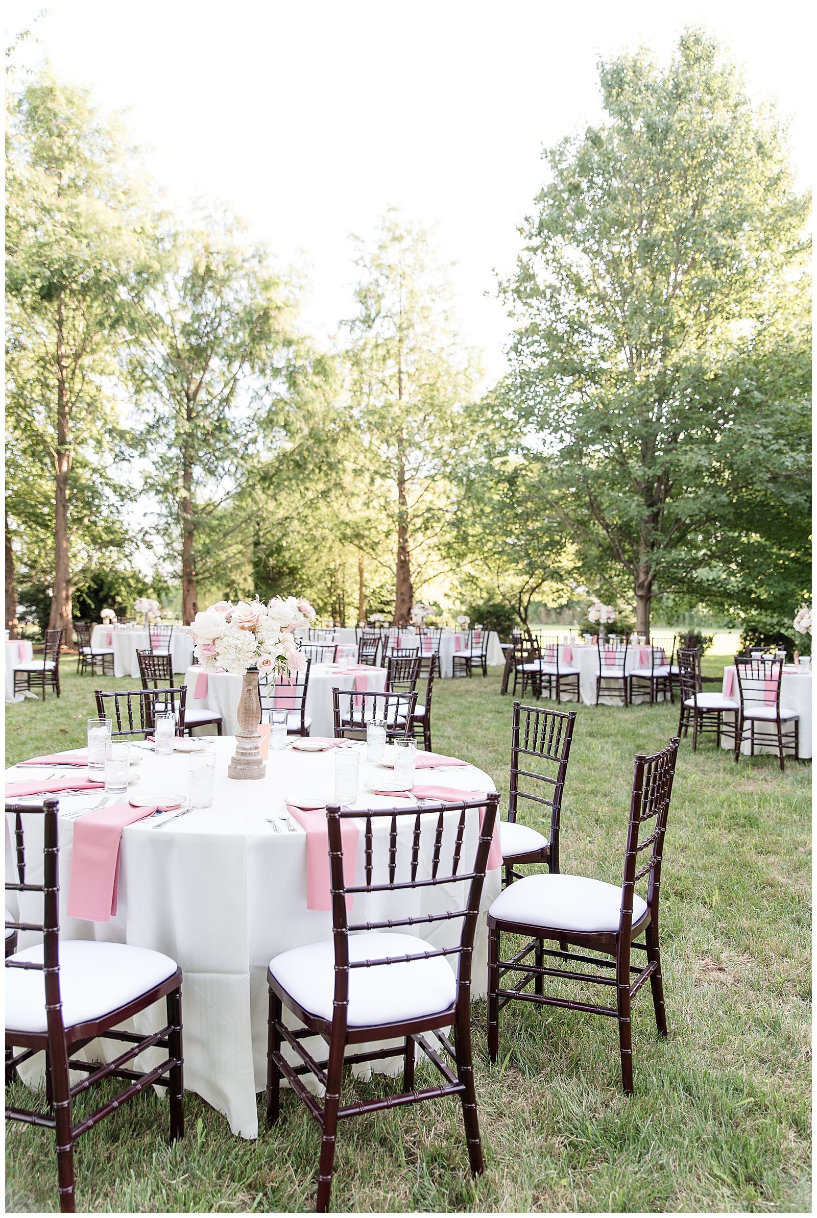 stunning outdoor reception area with white linens and pink napkins and beautiful flower centerpieces