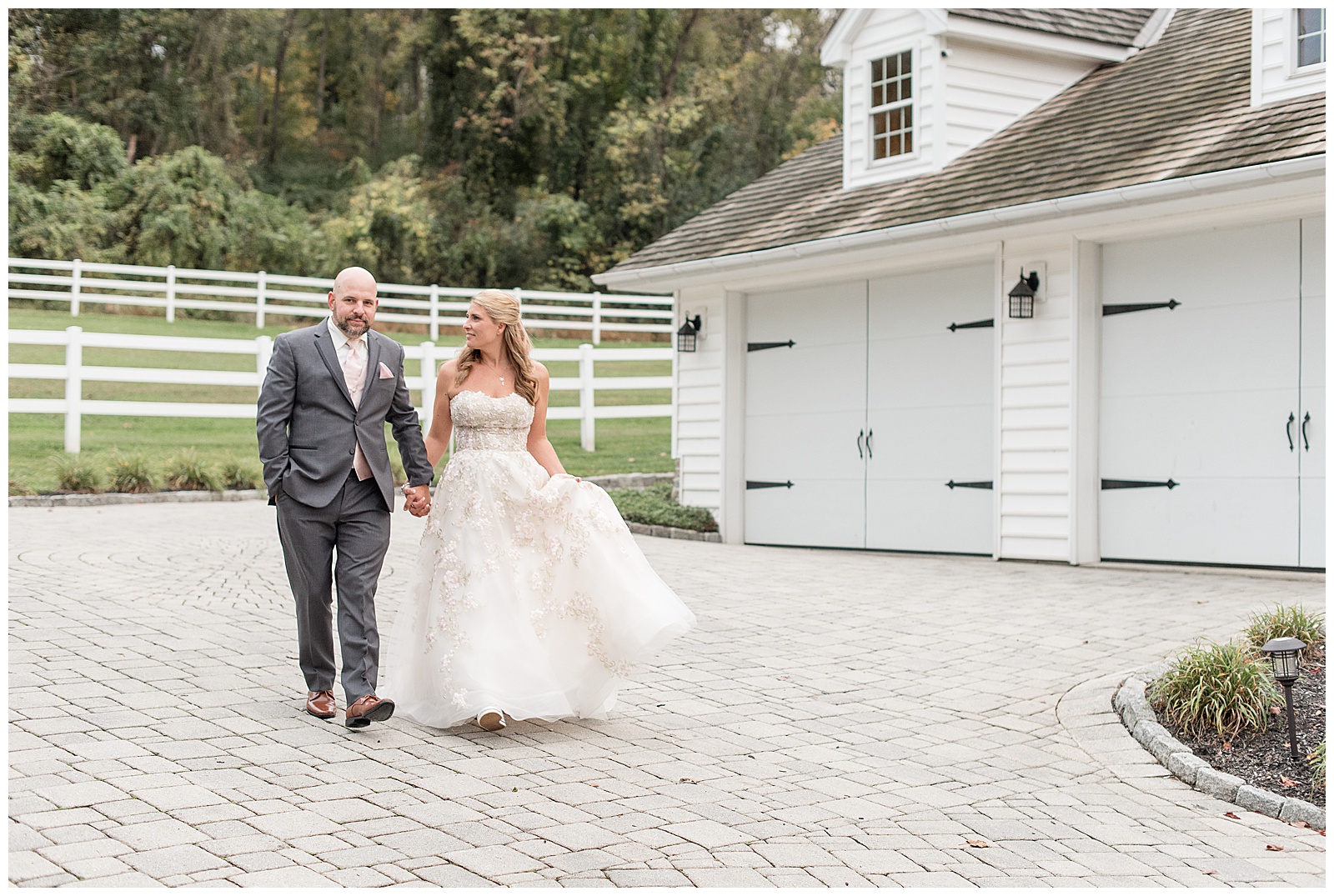 bride looking at groom holding hands walking towards camera on stone driveway at bluestone estate