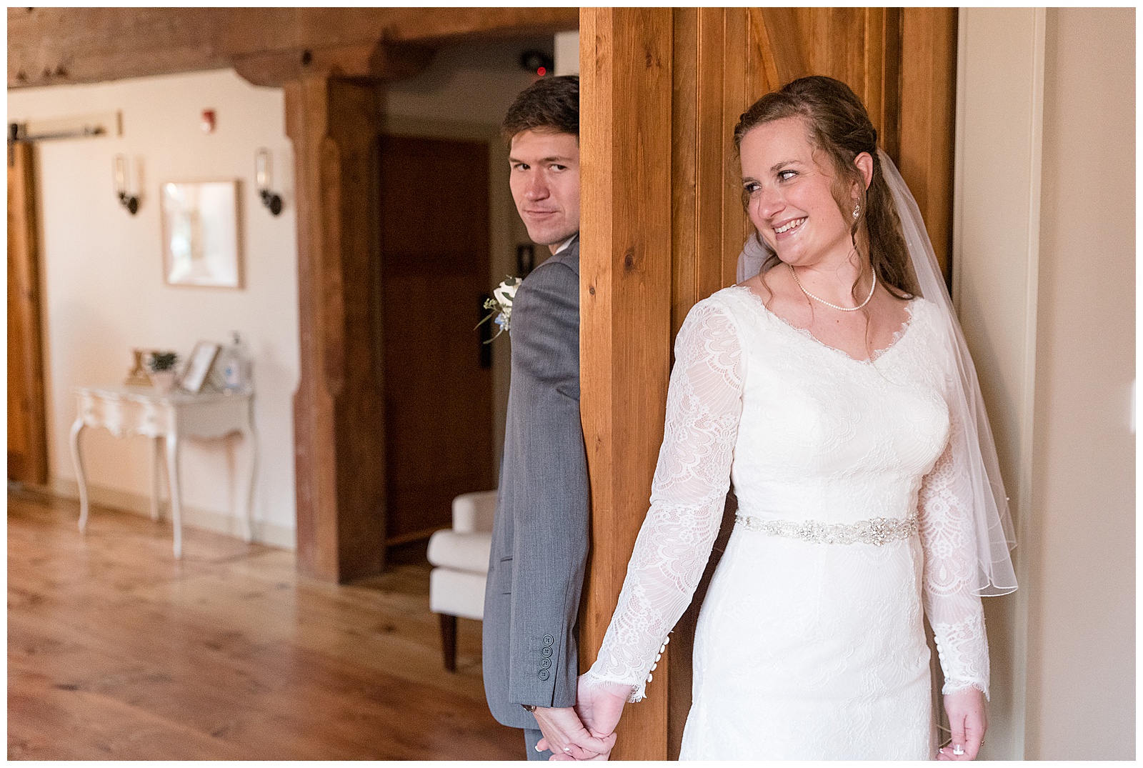 groom and bride on opposite sides of wooden door holding hands anticipating their first look on their wedding day