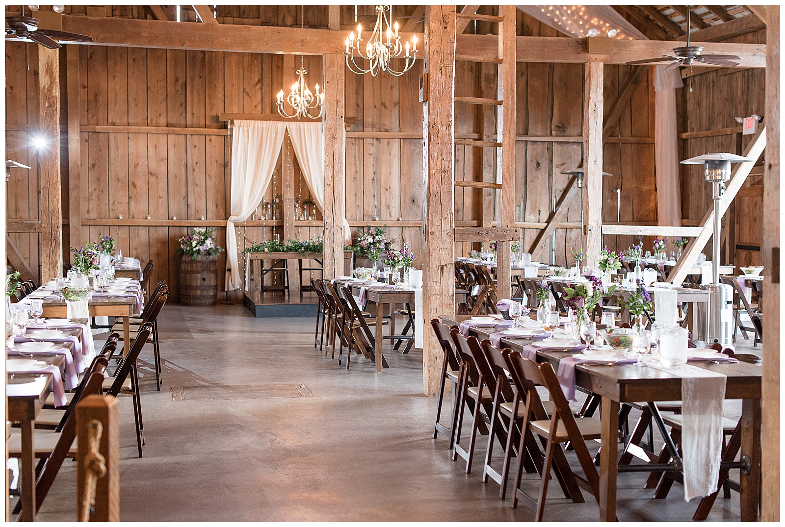 beautiful rustic barn reception area with exposed wooden beams, chandeliers, and wooden tables and chairs