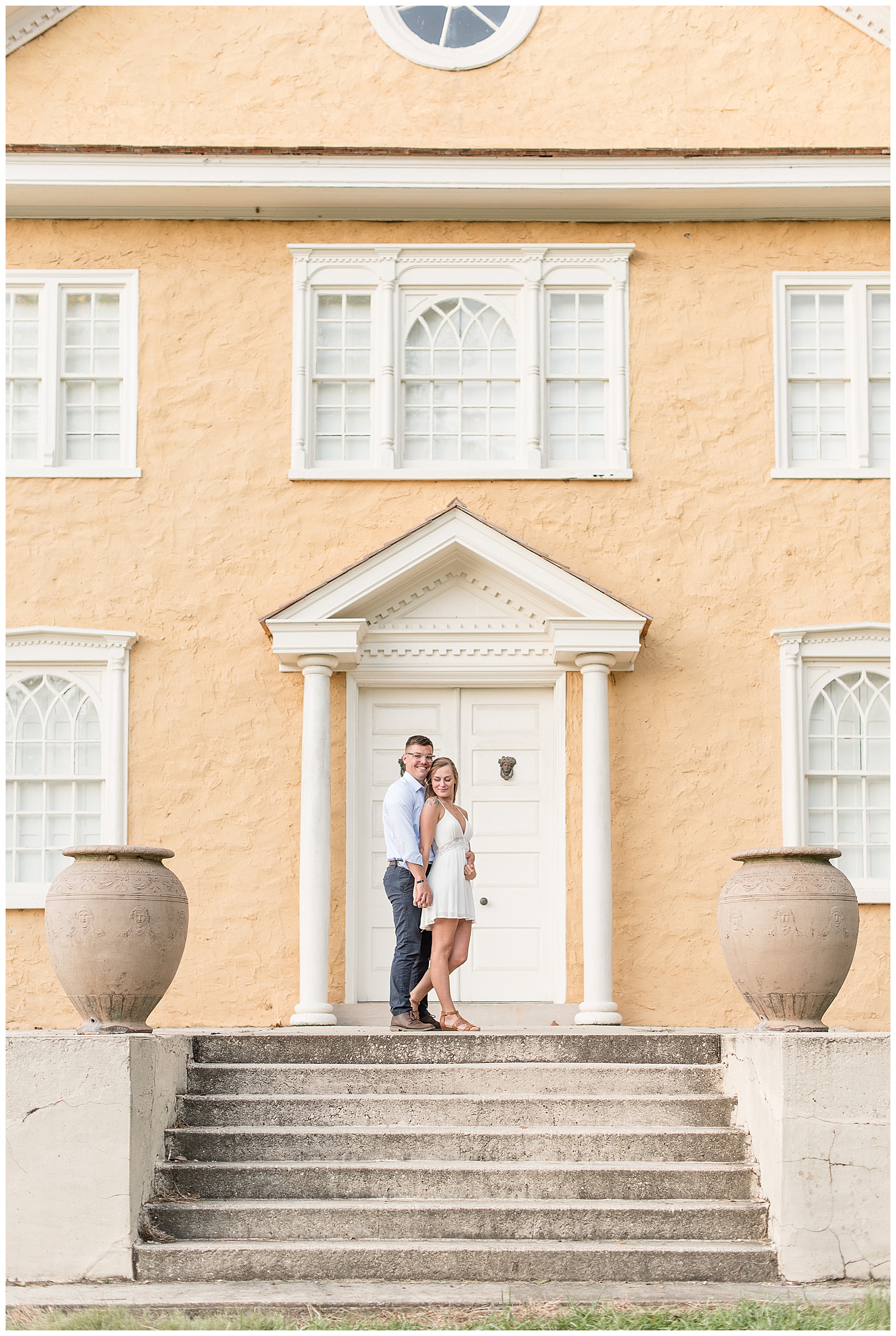 couple standing in front of yellow building, holding hands at top of stairs