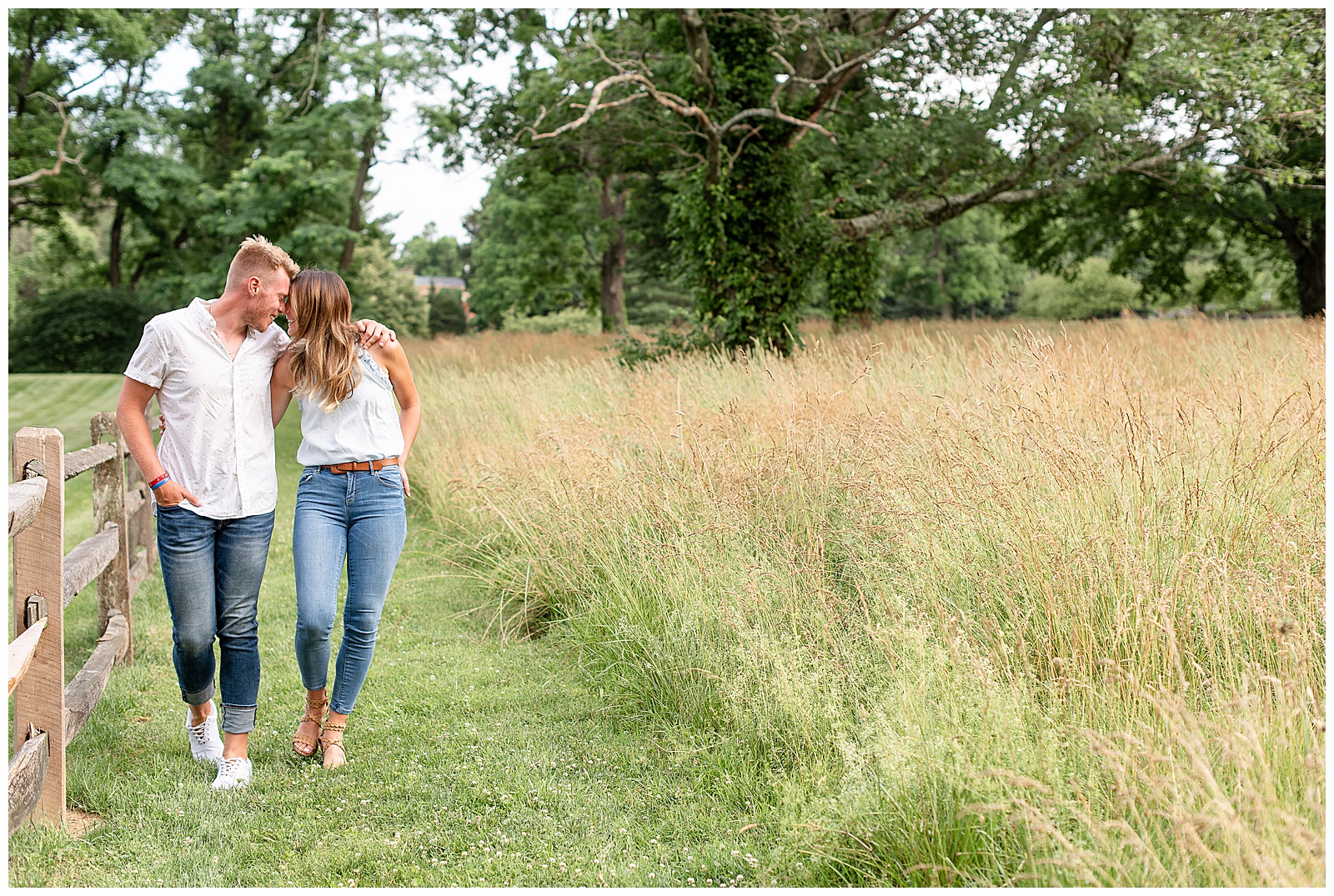 couple walking smiling at each other along edge of tall grass field