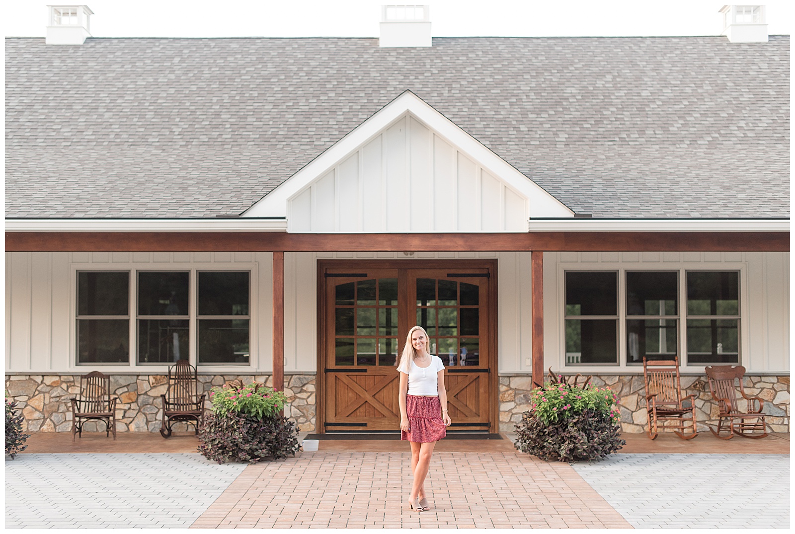 senior girl on brick walkway in front of modern barn with legs crossed in lancaster pennsylvania