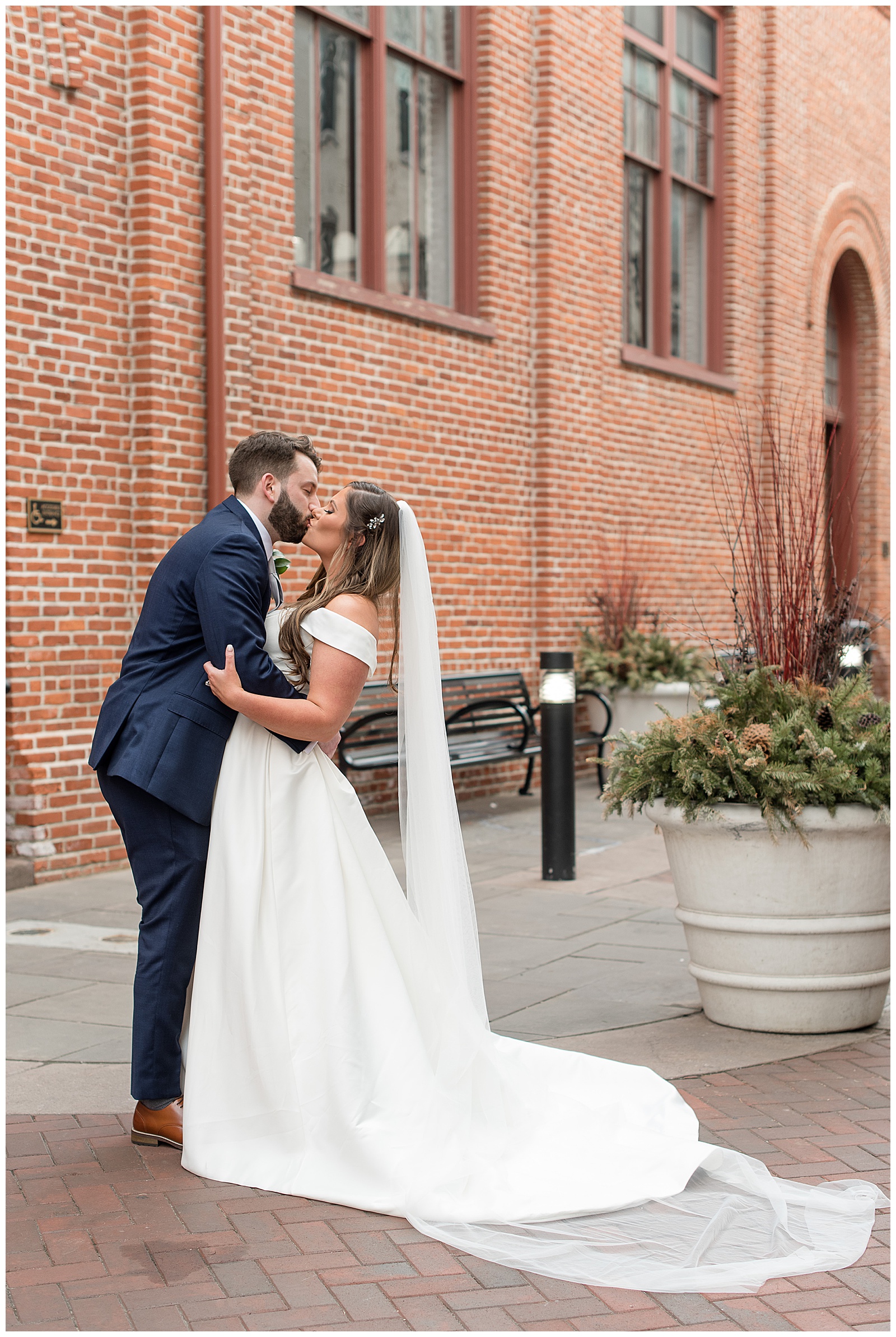 bride and groom standing close kissing next to central market in downtown lancaster pennsylvania