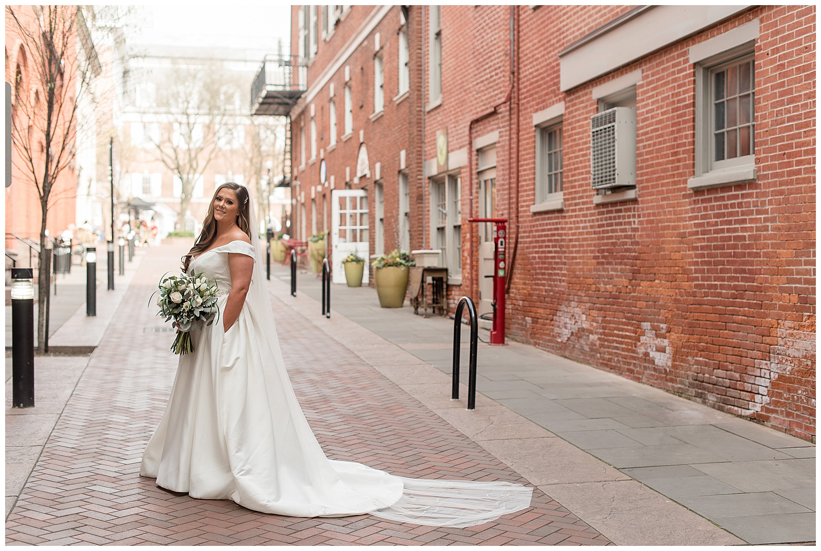 bride looking over left shoulder with hand in bridal gown pocket holding bouquet and smiling in lancaster pennsylvania