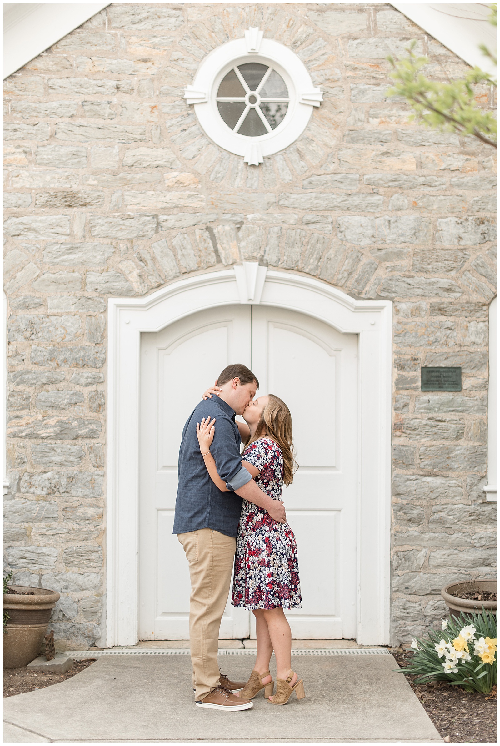 couple hugging tightly kissing in front of historical gray stone building in downtown lititz pennsylvania