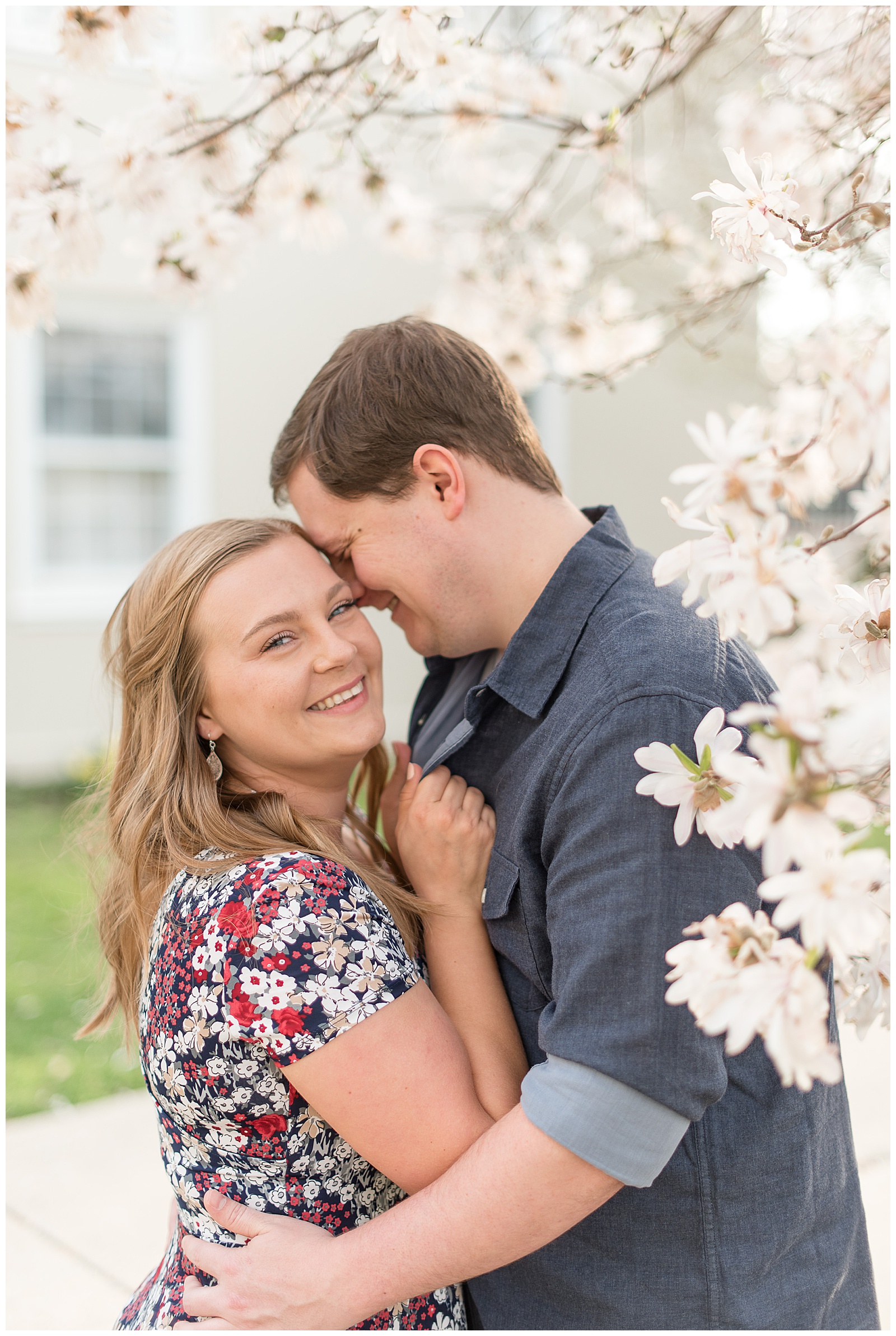 guy hugging girl and resting his forehead against hers as they smile by blooming tree in lancaster pennsylvania