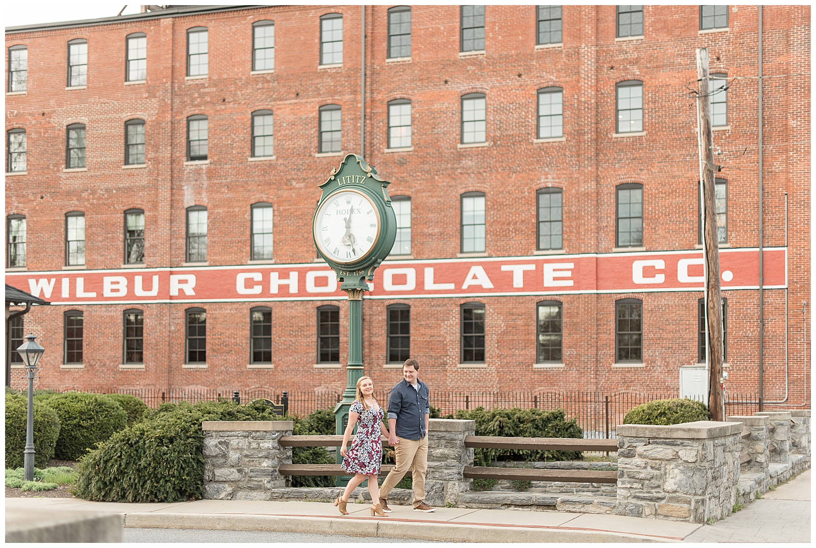 couple walking along sidewalk by historical wilbur chocolate factory building in downtown lititz pennsylvania