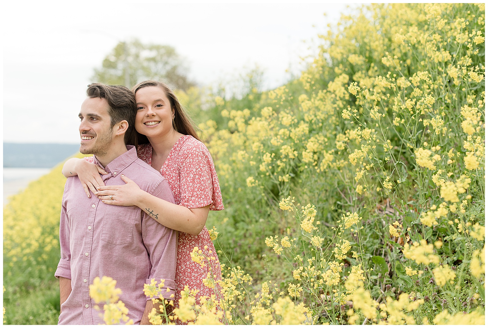 girl standing behind guy wrapping her arms around him both smiling in the middle of yellow wildflower field in harrisburg