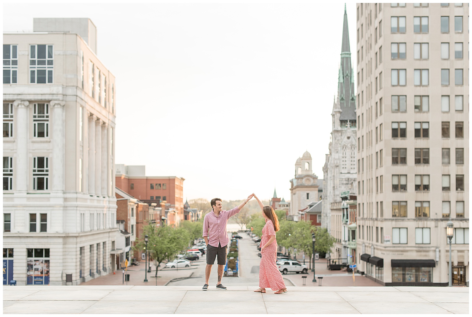 guy twirls girl under his left arm with cityline behind them on beautiful spring evening in harrisburg pennsylvania