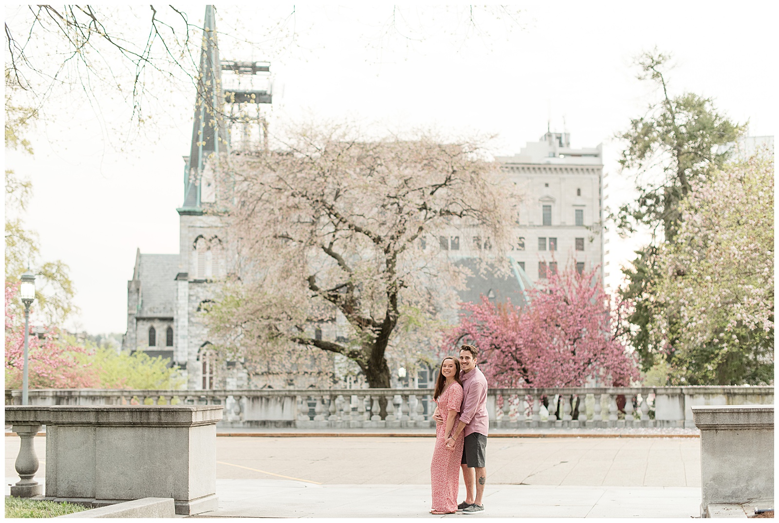 guy standing behind girl hugging her along front street in harrisburg pennsylvania with spring trees blooming behind them